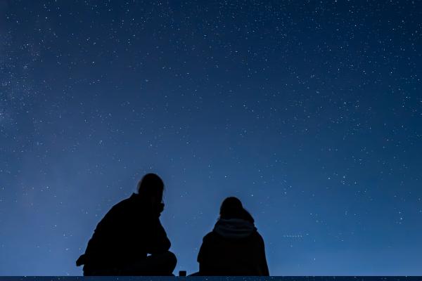 dos personas observan el cielo nocturno desde un mirador
