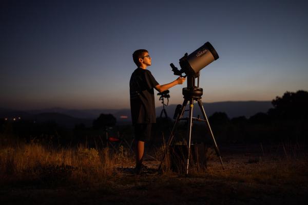 Imagen de una persona con observando el cielo con un telescopio